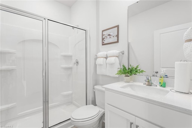 full bath with a stall shower, toilet, and vanity