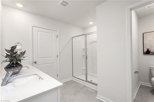 bathroom with toilet, a shower stall, recessed lighting, baseboards, and double vanity
