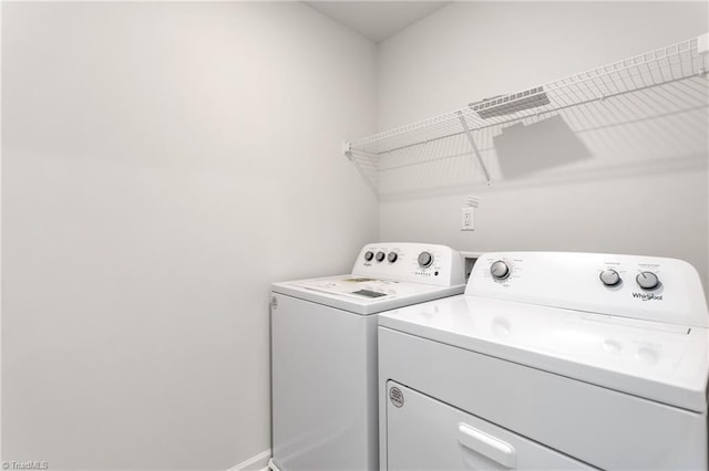 clothes washing area with washing machine and clothes dryer and baseboards