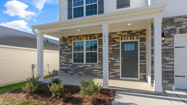 view of exterior entry with stone siding and covered porch