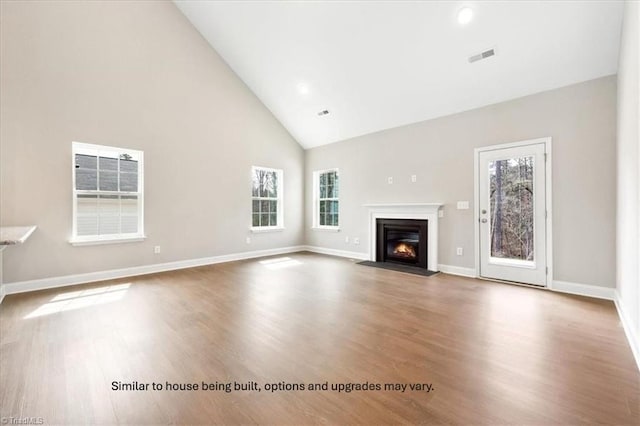 unfurnished living room with a fireplace with flush hearth, wood finished floors, visible vents, and high vaulted ceiling