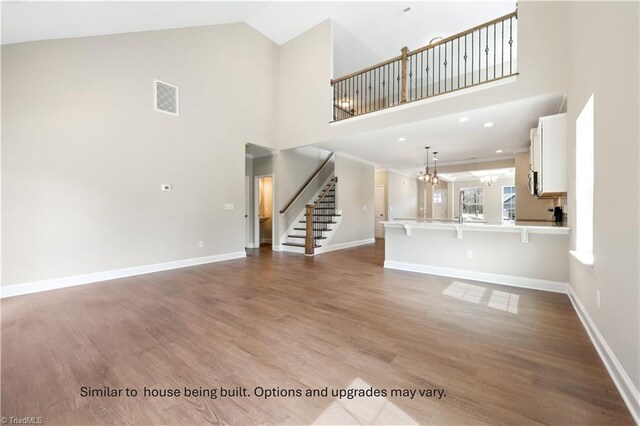 unfurnished living room with stairway, visible vents, high vaulted ceiling, and baseboards