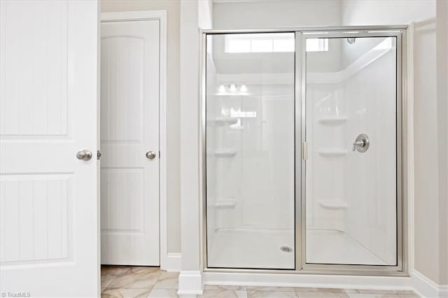full bath featuring baseboards, a stall shower, and marble finish floor
