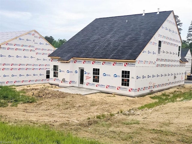 back of house featuring a shingled roof