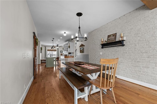 4420 Bunton Swaim Rd, Liberty, NC 27298 - dining room featuring a chandelier, brick wall, baseboards, and wood finished floors