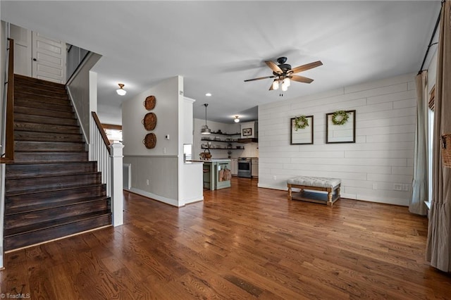 4420 Bunton Swaim Rd, Liberty, NC 27298 - unfurnished living room featuring a wainscoted wall, visible vents, dark wood-style flooring, ceiling fan, and stairs