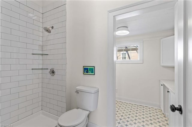 full bathroom with tiled shower, tile patterned floors, toilet, and baseboards