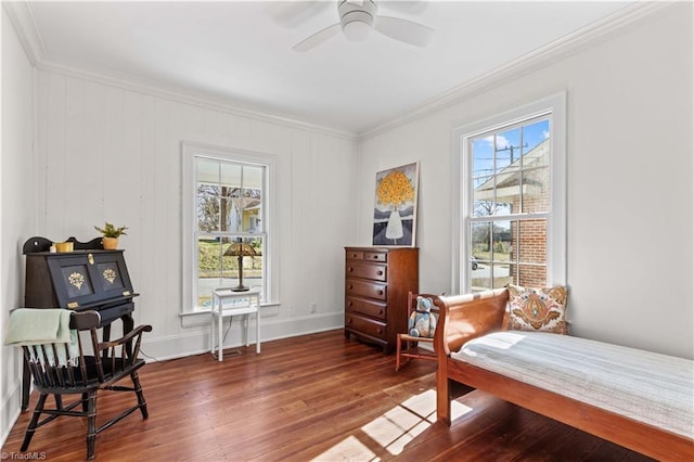 sitting room with a ceiling fan, crown molding, baseboards, and wood finished floors