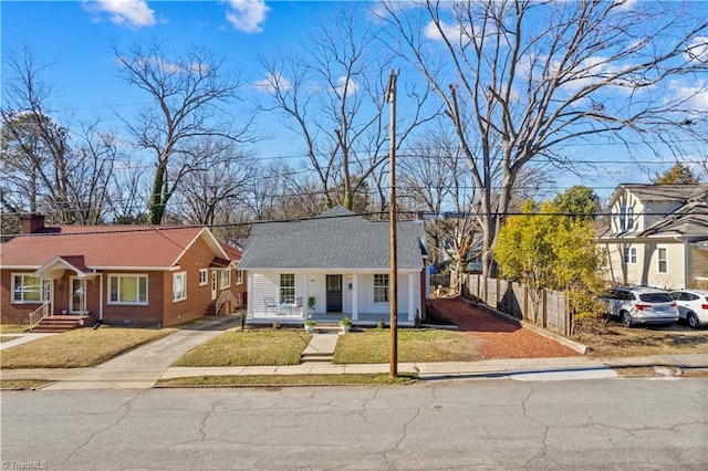 bungalow-style home featuring brick siding, covered porch, a front yard, crawl space, and fence