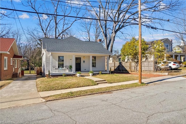 bungalow-style home featuring a shingled roof, fence, a porch, and a front yard