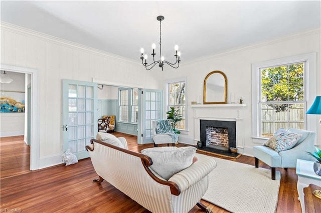 living area featuring crown molding, a healthy amount of sunlight, a fireplace, and wood finished floors