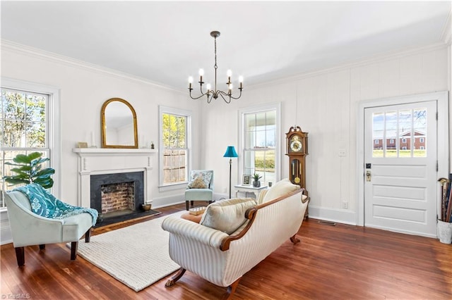 living room with baseboards, a fireplace with flush hearth, wood finished floors, crown molding, and a chandelier