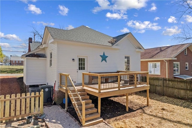 rear view of property with a shingled roof, fence, and a wooden deck