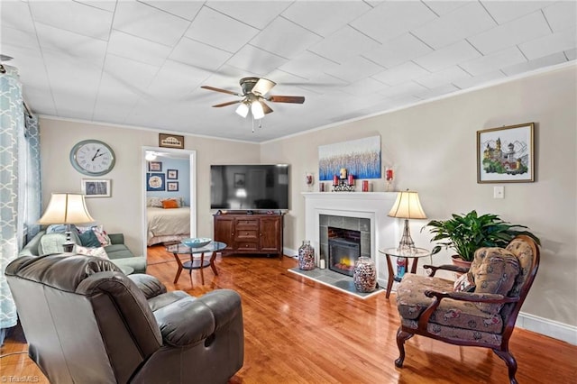 living room with hardwood / wood-style flooring, ornamental molding, and a tile fireplace