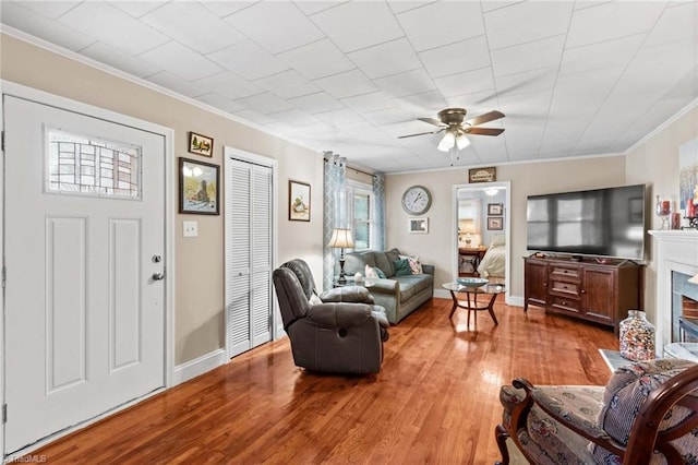 living room with ceiling fan, light hardwood / wood-style floors, ornamental molding, and a fireplace