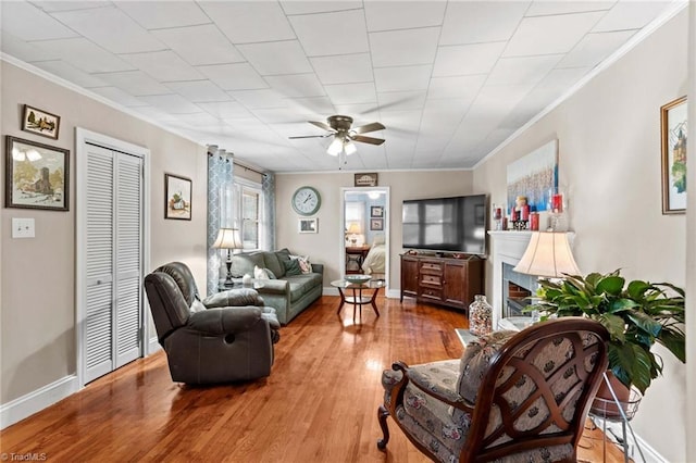 living room featuring crown molding, ceiling fan, and light hardwood / wood-style floors