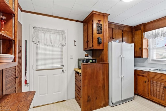 kitchen with white refrigerator, sink, and crown molding