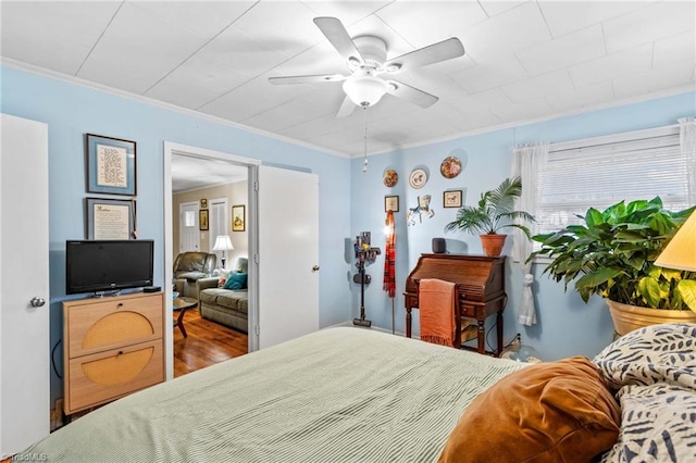 bedroom with hardwood / wood-style flooring, ceiling fan, and ornamental molding