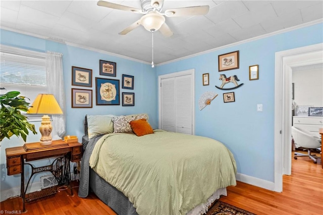 bedroom with hardwood / wood-style flooring, ceiling fan, crown molding, and a closet