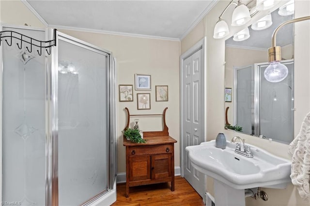 bathroom featuring hardwood / wood-style flooring, a shower with door, crown molding, and sink