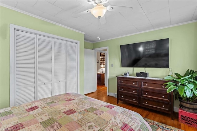 bedroom featuring ceiling fan, dark hardwood / wood-style flooring, ornamental molding, and a closet