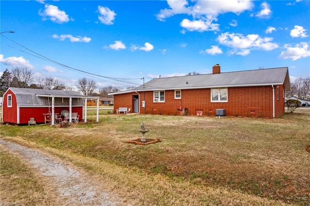 back of property with an outbuilding, central AC, and a lawn