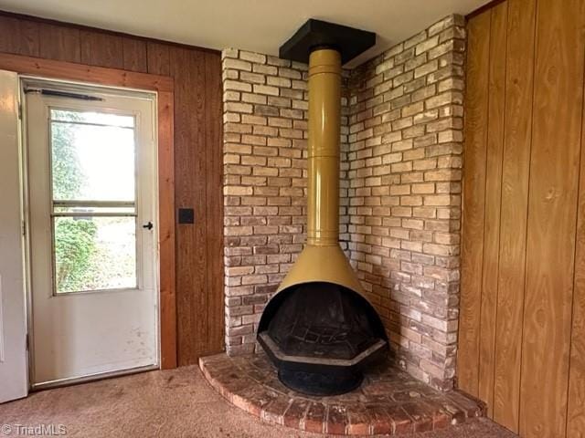 doorway to outside with a wood stove, carpet floors, healthy amount of natural light, and wooden walls
