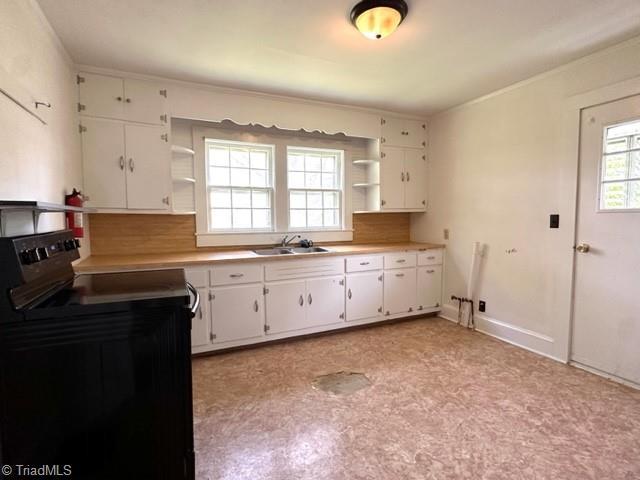 kitchen with open shelves, black range with electric stovetop, a sink, white cabinets, and light countertops