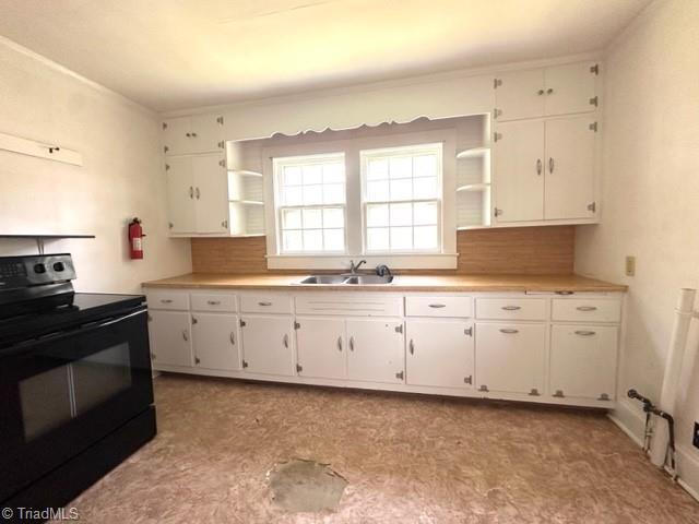 kitchen with black / electric stove, open shelves, a sink, and white cabinetry