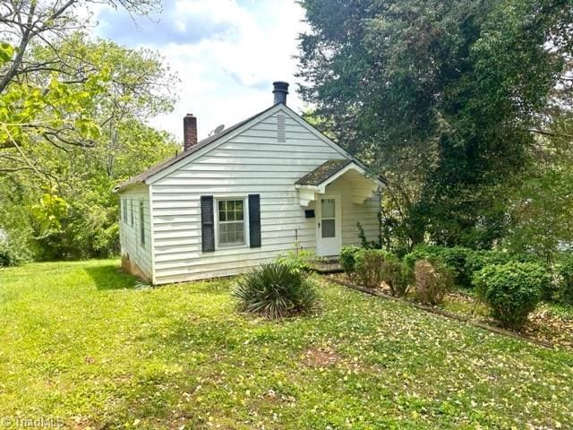 rear view of property with a chimney and a yard