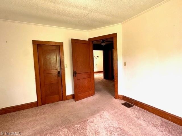 spare room featuring ornamental molding, light carpet, baseboards, and a textured ceiling