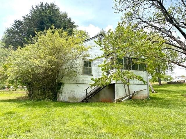 view of home's exterior with a lawn and stairs