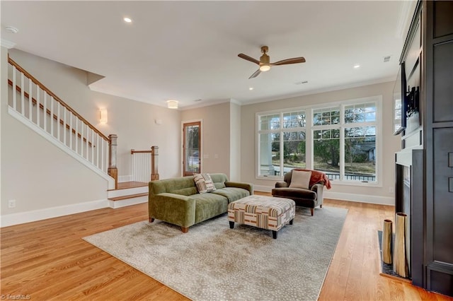 living room with ornamental molding, ceiling fan, and light hardwood / wood-style flooring