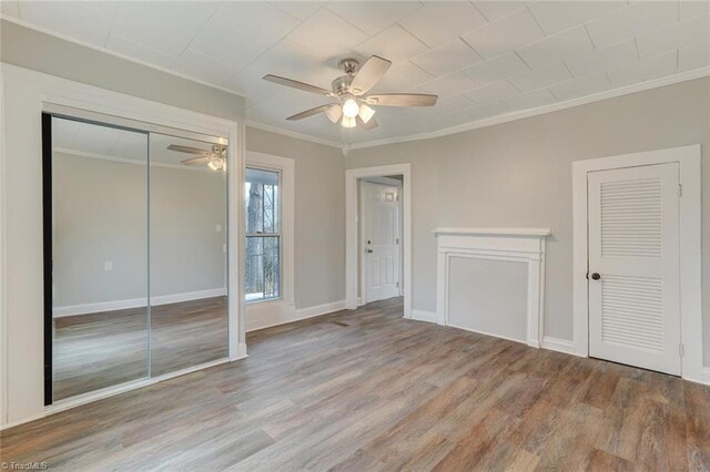 unfurnished bedroom featuring ornamental molding, light hardwood / wood-style floors, ceiling fan, and multiple closets