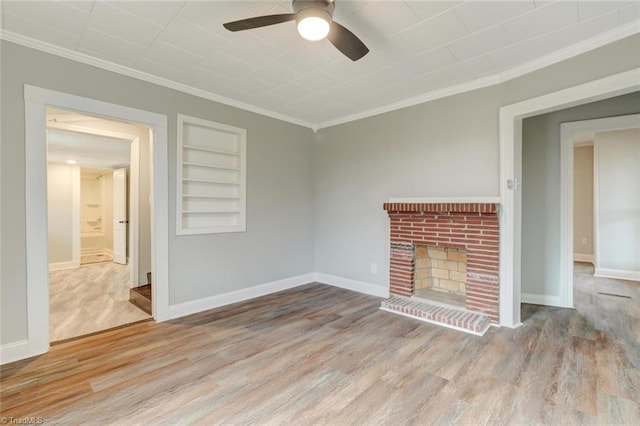 unfurnished living room with light hardwood / wood-style flooring, a brick fireplace, ceiling fan, ornamental molding, and built in features