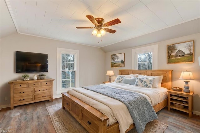 bedroom with multiple windows, ceiling fan, wood-type flooring, and vaulted ceiling