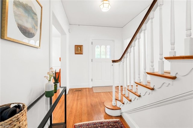 entrance foyer featuring baseboards, light wood finished floors, and stairs