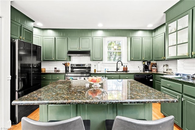 kitchen with a kitchen breakfast bar, a sink, green cabinets, black appliances, and under cabinet range hood