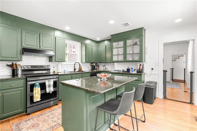 kitchen with a sink, green cabinetry, under cabinet range hood, and double oven range