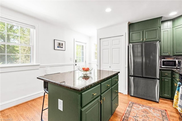 kitchen featuring plenty of natural light, green cabinetry, stainless steel appliances, and light wood-style flooring