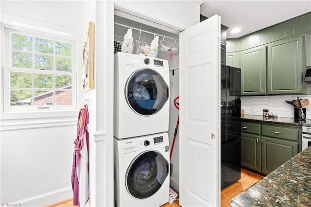 laundry area with laundry area, stacked washer and clothes dryer, and light wood-style flooring