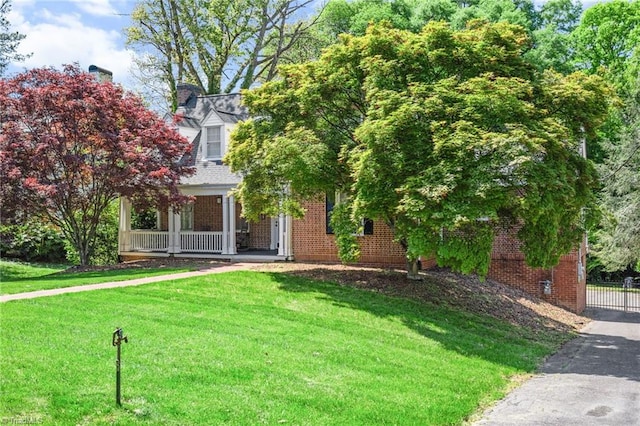 view of front of property with fence, a porch, a front lawn, and brick siding