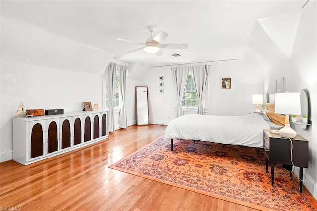 bedroom with baseboards, ceiling fan, wood finished floors, and vaulted ceiling
