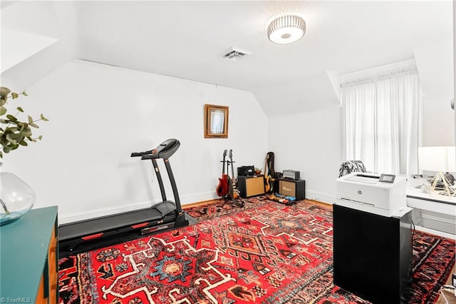 exercise area with visible vents, baseboards, and lofted ceiling