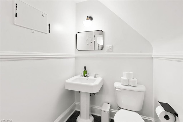 half bathroom with baseboards and toilet