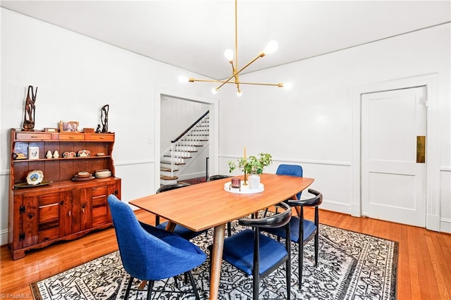 dining room with stairway, light wood-type flooring, and a chandelier