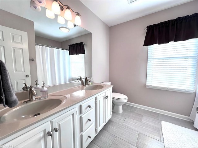 bathroom featuring a wealth of natural light, vanity, and toilet