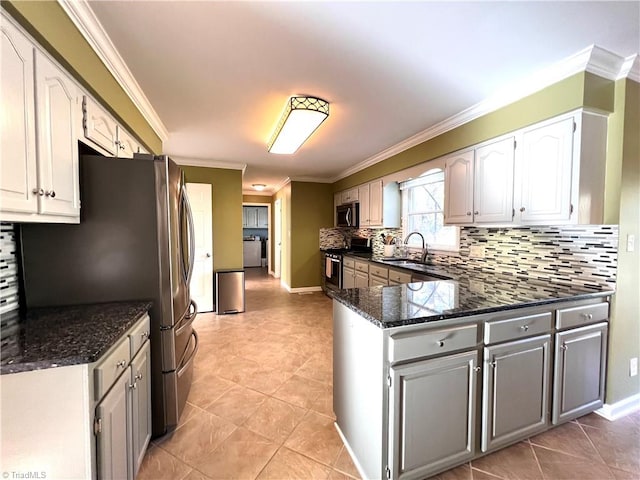 kitchen featuring ornamental molding, stainless steel appliances, sink, dark stone countertops, and white cabinets