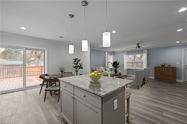 kitchen featuring decorative light fixtures, ceiling fan, light wood-type flooring, and ornamental molding