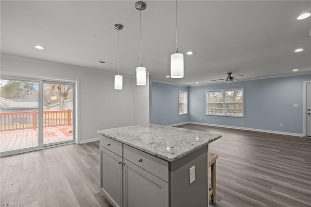 kitchen with ceiling fan, light stone countertops, ornamental molding, decorative light fixtures, and light hardwood / wood-style floors